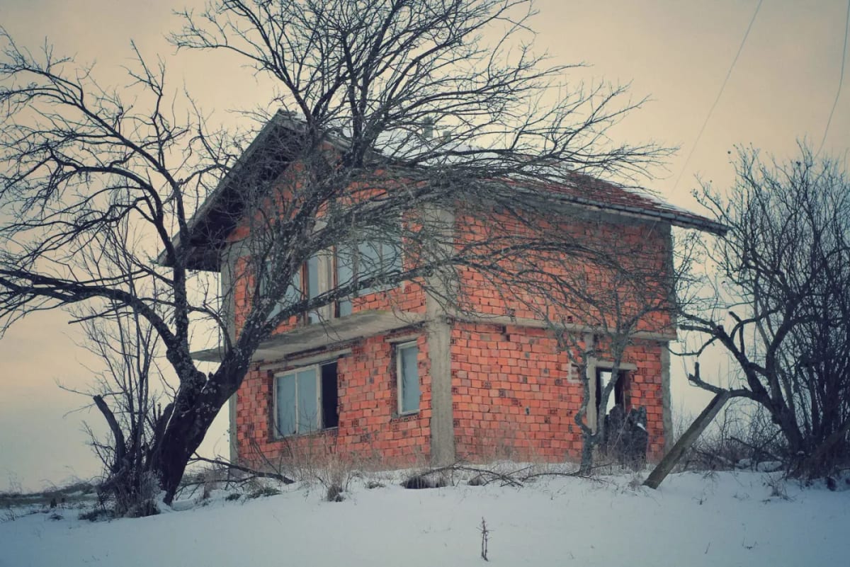 Une maison de village bulgare inachevée et abandonnée, sous la neige